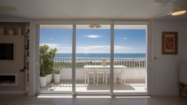 Quarto com porta de vidro deslizante que dá para uma varanda com vista para o mar.