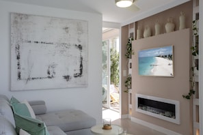 Ein Wohnzimmer mit einem großen abstrakten Gemälde, einem Sofa, einem Kamin und einer Strandansicht an der Wand.