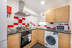 Cocina compacta con estufa, microondas, horno y lavadora.