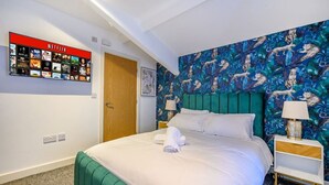 Ein Hotelzimmer mit Bett, einem an der Wand montierten Netflix-Bildschirm, einer Tür und einer Wand mit Muster.