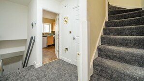A staircase leading to a second floor, a kitchen area with wooden cabinets, and a door with a circular decoration.