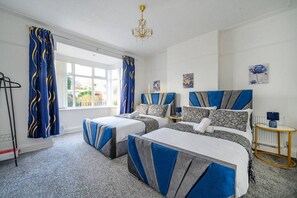 Ett hotellrum med två sängar, en kristallkrona, konstverk på väggarna och utsikt genom fönstret.