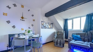 Un soggiorno moderno con zona pranzo, poltrona massaggiante e divano illuminato di blu.