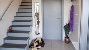 Un escalier menant à une porte, une plante en pot et un jouet en peluche sur le sol.