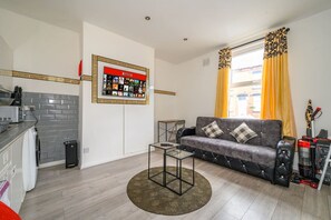 A living room with a grey sofa, a coffee table, a TV mounted on the wall, and a window with yellow curtains. - *A23S* for your most relaxed & Cosy stay + Parking (West Yorkshire)