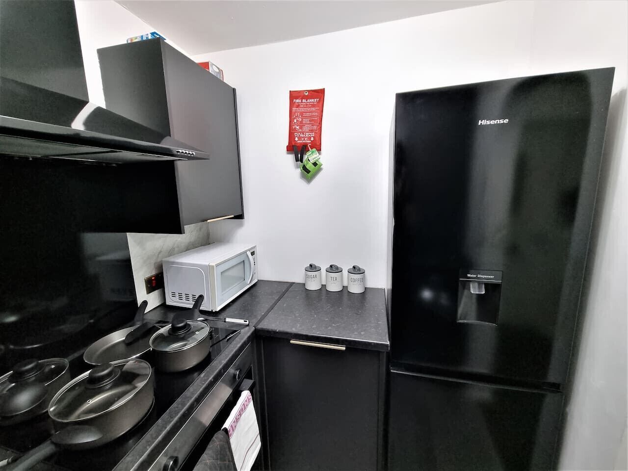 Una cocina equipada con estufa, microondas, armarios y refrigerador.