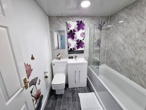 A bathroom with a toilet, sink, and shower. - Stylish Home with Hot Tub and WiFi (Morley)