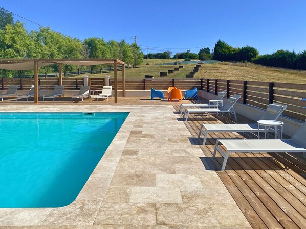 Une piscine avec des chaises longues et une terrasse en bois.