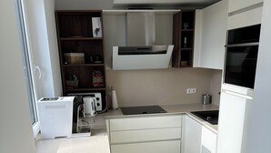 Una cocina moderna con armarios blancos, horno empotrado y ventana que proporciona luz natural.