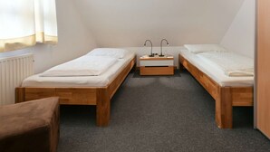 Eine kleine, einfache Unterkunft mit zwei Holzbett und einem Tisch sowie einem Stuhl.