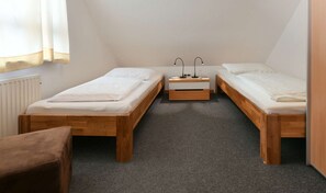 A small, single-room accommodation with two wooden beds, a small table, and a chair. - Pinkenburg Süd in the Kleine Pinkenburg House on Wangerooge (Wangerooge)