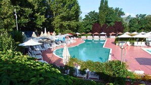 A pool area with lounge chairs and umbrellas, surrounded by greenery. - 5-person Mobile Home Near Chianti (Bucine)