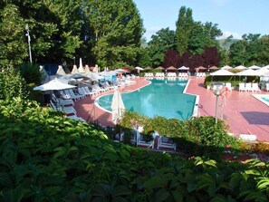 A pool area with lounge chairs and umbrellas, surrounded by greenery. - 5-person Mobile Home Near Chianti (Bucine)