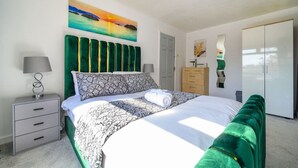 A bedroom with a bed, a nightstand, a dresser, a wardrobe, and a painting on the wall. - Stylish Home with Hot Tub in Hawksworth (Hawksworth)