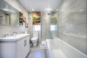Une salle de bain moderne avec une douche à parois de verre, des toilettes et une baignoire.