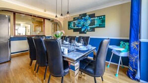 A dining area with a table set for four, black chairs, and a decorative wall piece. - Stylish Home with Hot Tub in Hawksworth (Hawksworth)