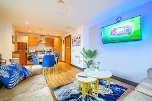 Ein modernes Wohnzimmer mit einer Couch, einem Couchtisch und einem an der Wand befestigten Fernseher.