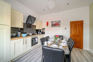 A modern kitchen with white cabinets, a dining table set for four, and a chandelier.