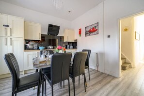 A modern kitchen with white cabinets, a dining table with chairs, and a staircase leading to an upper level.