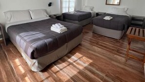 A room with two beds, a ceiling fan, a mirror, and a wooden floor. - Hosteria Cumbres Blancas (Esquel)