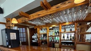 A bar area with wooden beams, stone walls, and bar stools. - Hosteria Cumbres Blancas (Esquel)