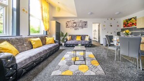 A modern living room with a sofa, a coffee table, and a kitchen area in the background. - Stylish Ground Floor Apartment in West Yorkshire (West Yorkshire)