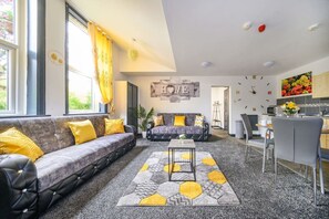 A modern living room with a sofa, a coffee table, and a kitchen area in the background.