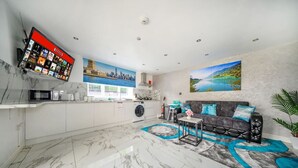 Eine moderne Küche mit Einbauwaschmaschine, Flachbildfernseher und Essbereich mit Sofa und Tisch.