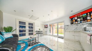 Ein modernes Wohnzimmer mit einer Couch, einem Couchtisch und einer TV-Wand mit Netflix.