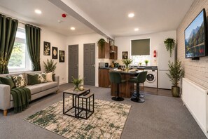 Ein modernes Wohnzimmer mit einer Couch, einem Couchtisch und einer Küchenzeile mit Esstisch und Stühlen.