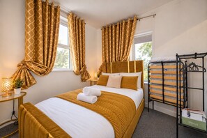 A hotel room with a bed, curtains, a bedside table with a lamp, and a luggage rack. - *F9GH* for your most relaxed & Cosy stay+Parking (West Yorkshire)