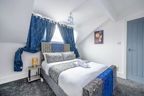 A bedroom with a bed, a nightstand, a lamp, a window with curtains, a door, and a wall with a picture. - *16PT* For your relaxed & Cosy stay + Free Parking (Armley)