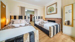 Quarto de hotel com duas camas, lareira, espelho e porta.