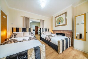 Une chambre d’hôtel avec deux lits, une cheminée, un miroir et une porte.
