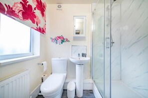 Une salle de bain comprenant des toilettes, un lavabo, une douche et une fenêtre.