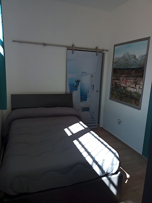 Una camera da letto con un letto, una finestra vista montagna e una porta con pannello di vetro.