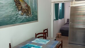 A dining area with a table set for four, a painting of a coastal scene, and a sliding door leading to a bedroom. - De Luxe Apartment just 150 m from the Sea in Central Giulianova (Giulianova)