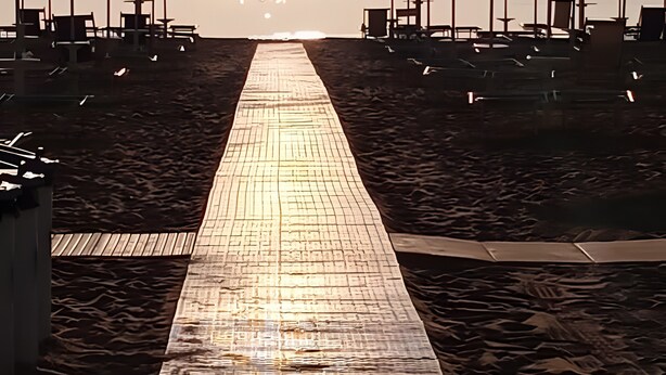 A beach walkway leading to beach umbrellas, with a clear sky and sun setting in the background. - De Luxe Apartment just 150 m from the Sea in Central Giulianova (Giulianova)