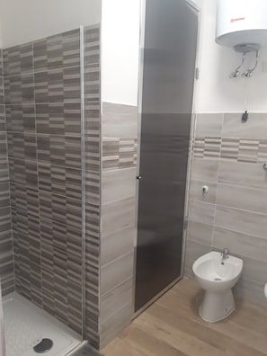 Un bagno con doccia, un water e un bidet.
