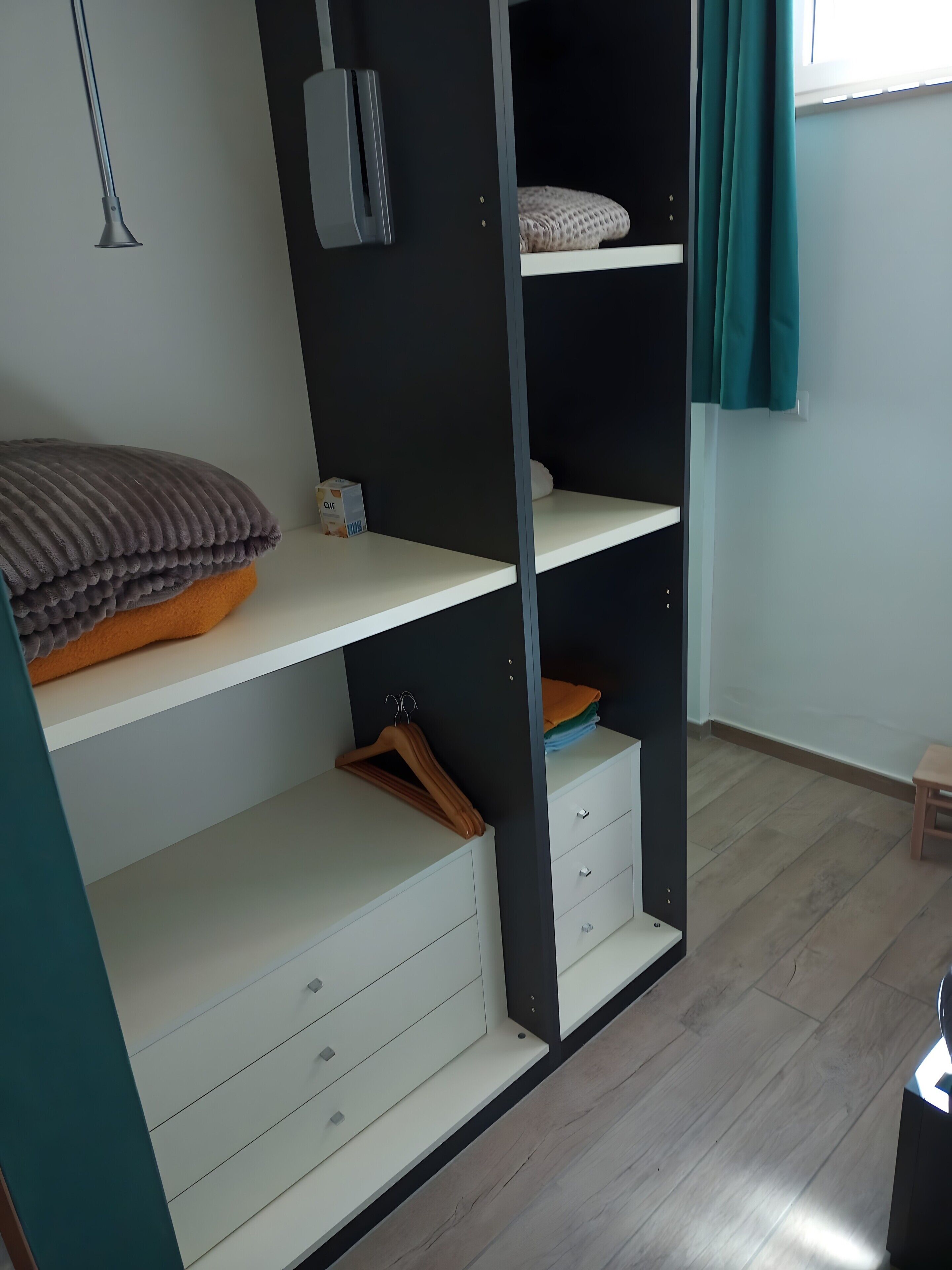 A room with a bed, a wardrobe, a heater, and a window with curtains.