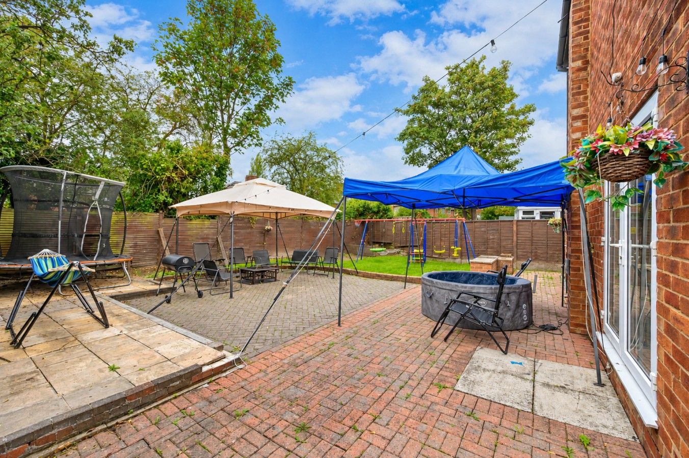 Un jardin avec un espace patio, des sièges d’extérieur, un jacuzzi et une balançoire.