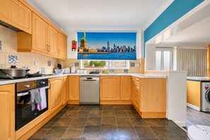 A modern kitchen with wooden cabinets, a dishwasher, and a stove. - Stylish Family Home with Hot Tub (West Yorkshire)