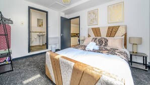 Een hotelkamer met een bed, een badkamer, een kroonluchter en kunstwerken aan de muren.