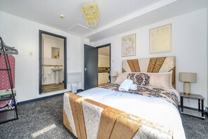 Ein Hotelzimmer mit Bett, Badezimmer, einer Lüster und Kunstwerken an den Wänden.