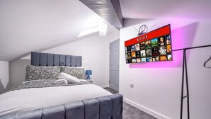 A bedroom with a bed, a wall-mounted TV displaying Netflix content, and a door. - Stylish Home with Free Parking (West Yorkshire)