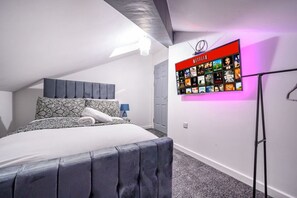 Een slaapkamer met een bed, een aan de muur bevestigde televisie waarop Netflix wordt afgespeeld, en een deur.