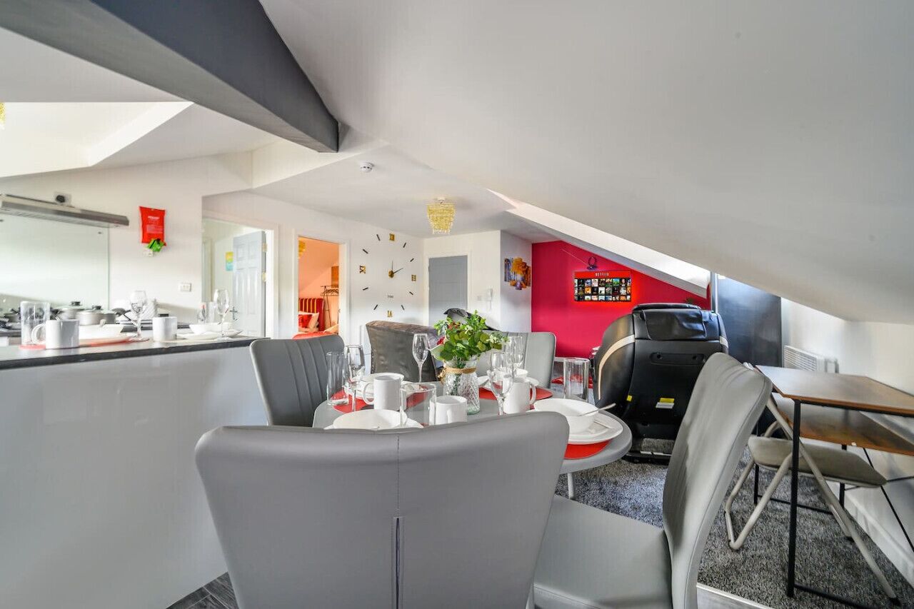 Una cocina moderna con comedor, pared de acento roja y techo con tragaluces.