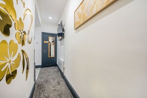 A hallway with a door, a radiator, and a wall with gold leaf artwork. - *F19GH* For relaxed & Cosy stay/Free Parking/WiFi (West Yorkshire)