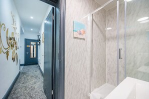 Un couloir doté d’un sol recouvert de moquette, d’une porte avec un miroir et d’un mur orné d’un motif décoratif.