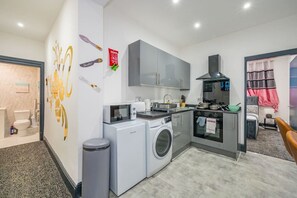 Une cuisine compacte équipée d’un lave-linge, d’un four à micro-ondes et d’une cuisinière.